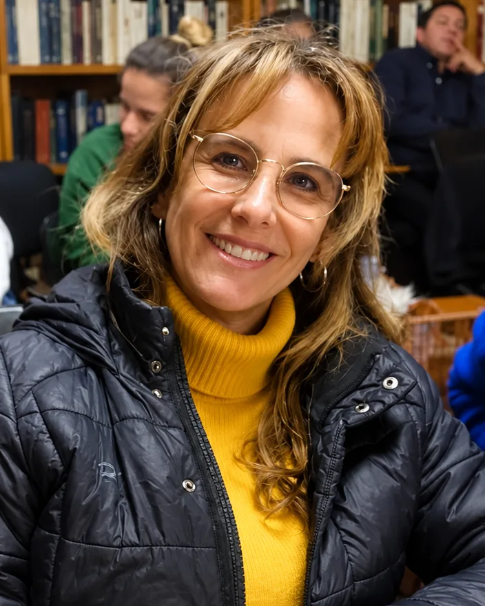 Mariana Albert sonriendo en una clase, con una biblioteca de fondo.